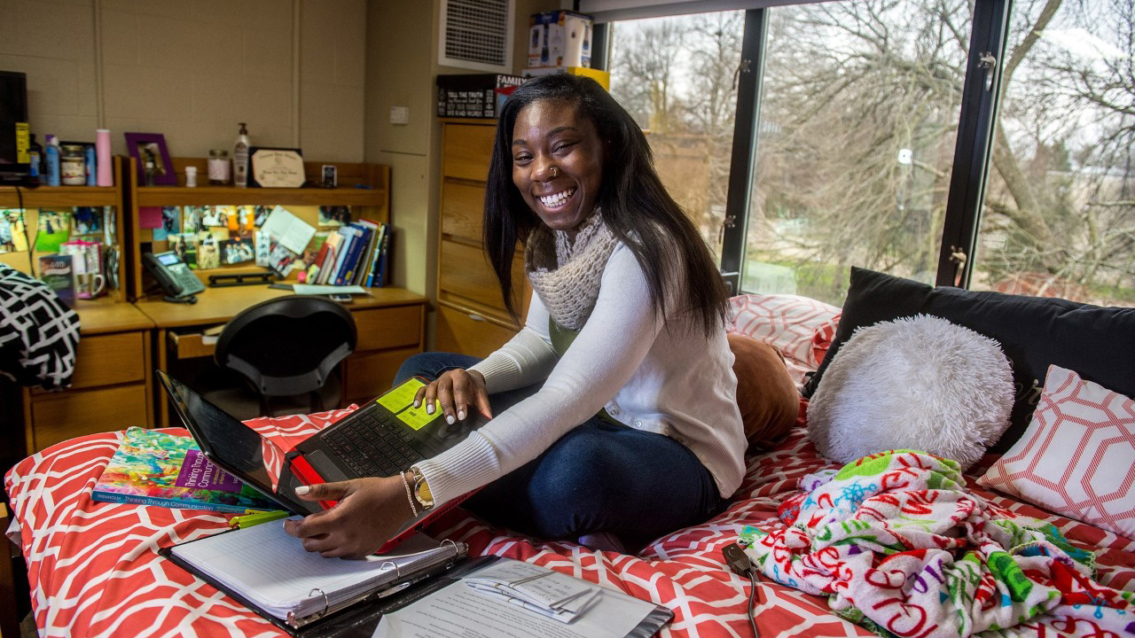 Student on bed in dorm room