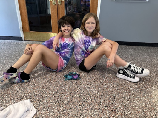Two children sitting on the ground with arms around each other