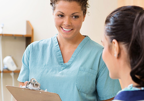 Clinical medical assistant holding clipboard with patient
