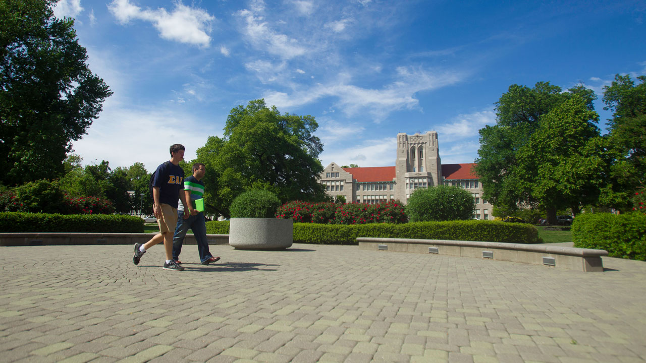 Two students walking across the front oval