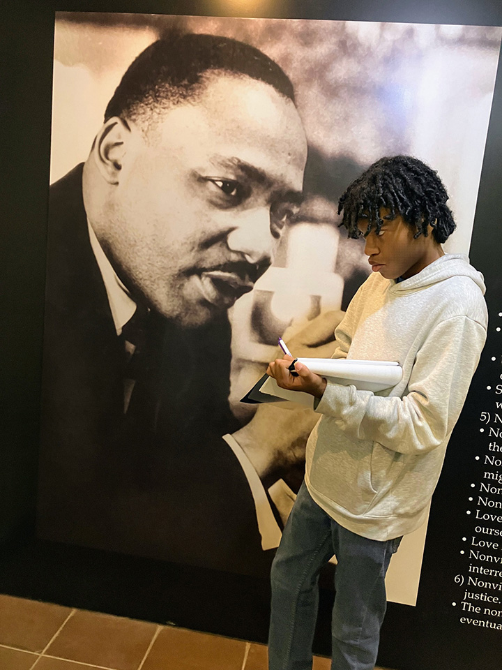 Student standing in front of large photo of MJKJ.