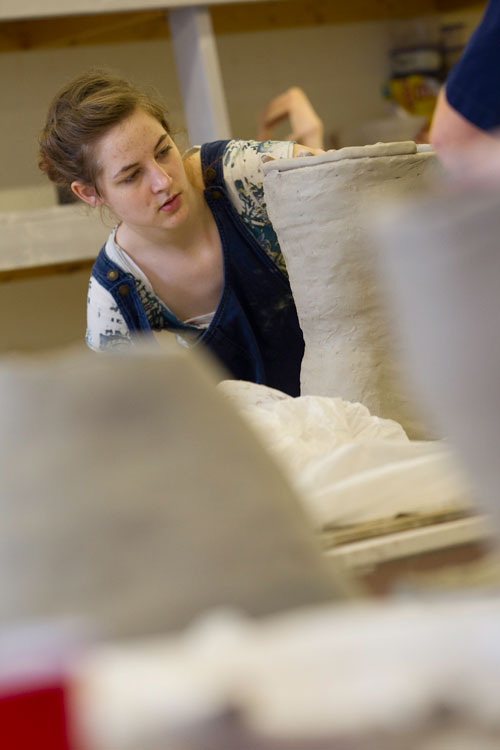 Female student sculpting ceramics in art
