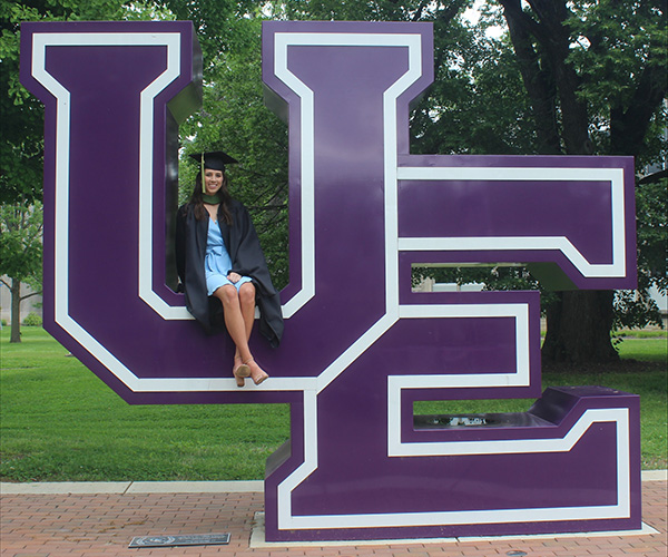 Emma Thomas sitting on UE sign