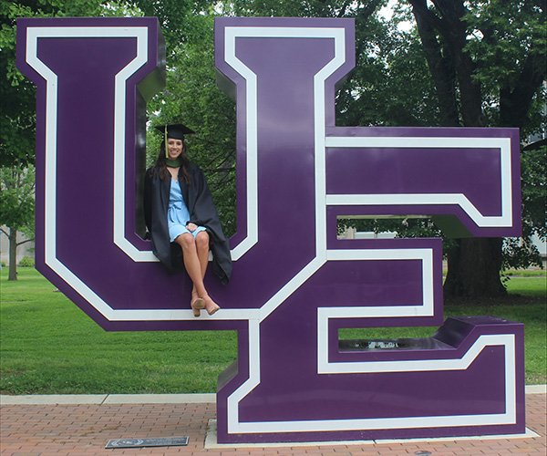 Emma Thomas sitting on UE sign