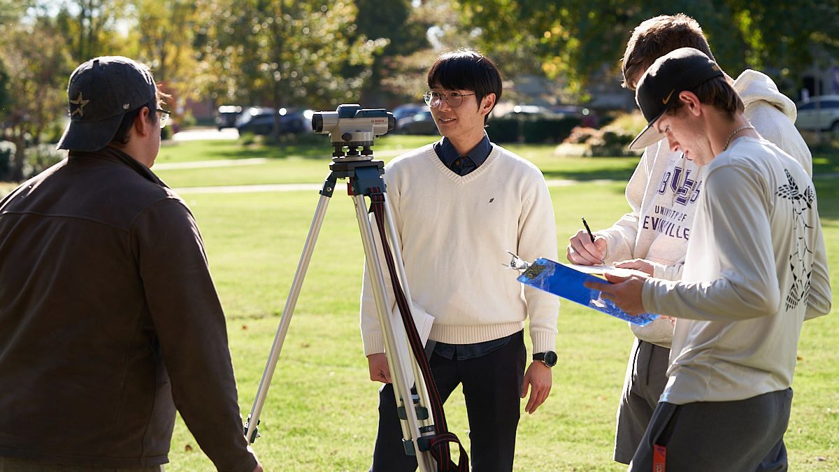 Professor supervises group of students conducting engineering survey.