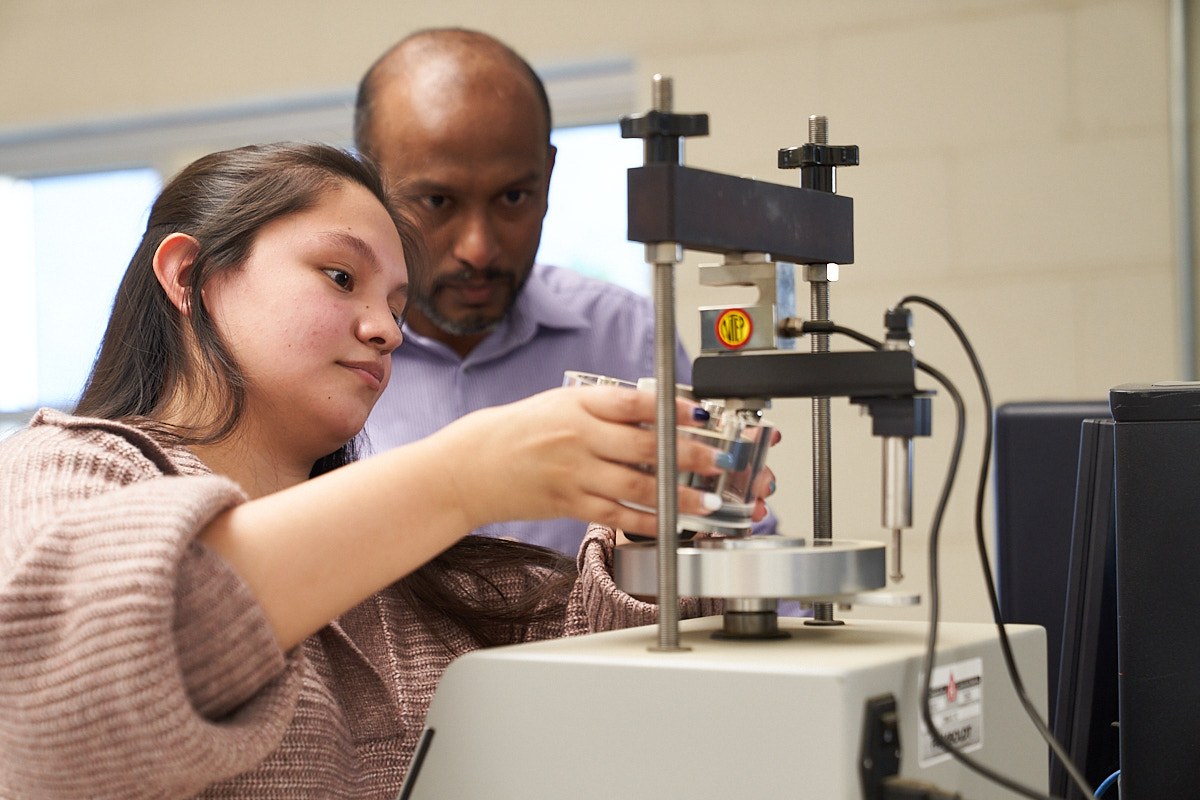 Student and professor examine soil lab equipment.