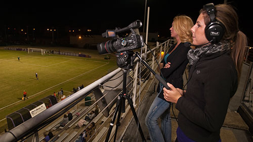 Students recording soccer game at night