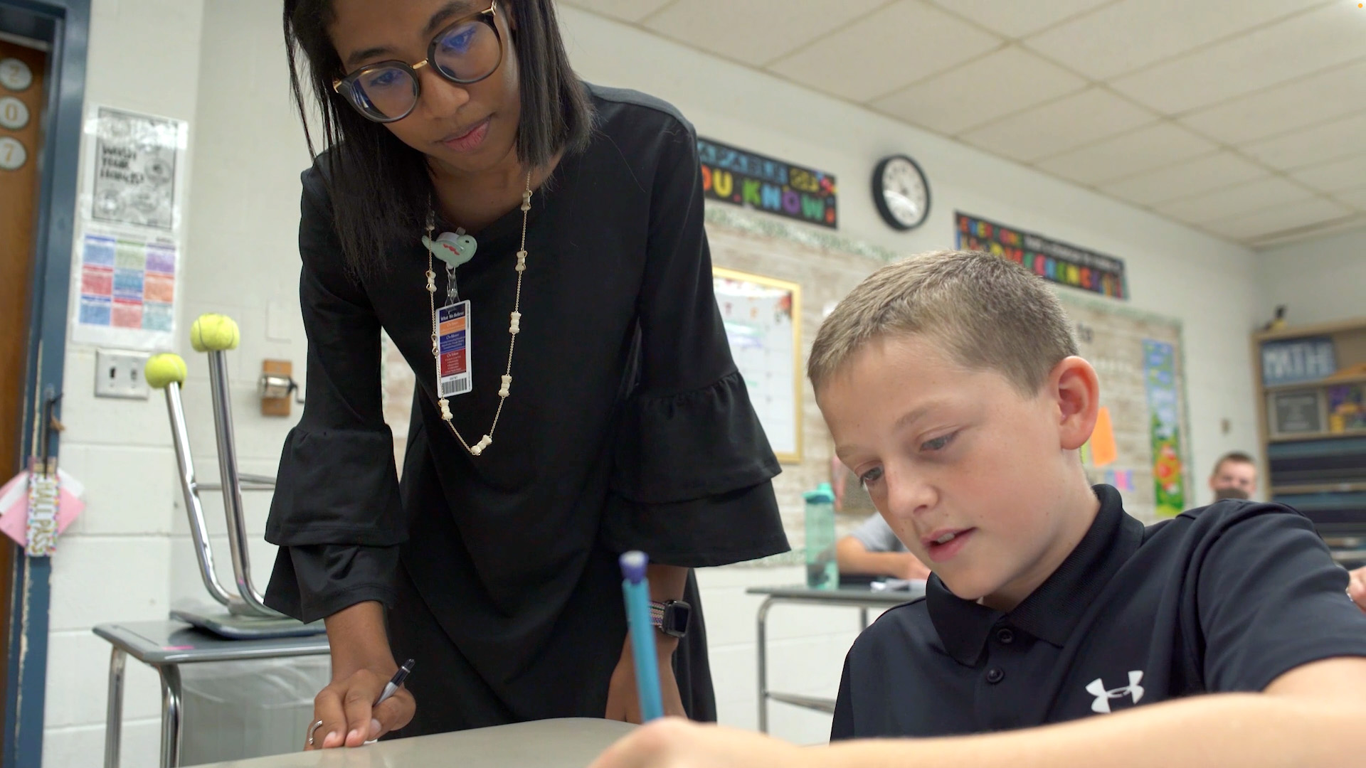 Education teacher in class with grade school student