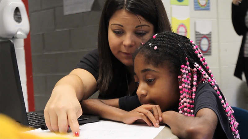 Education student helping child read