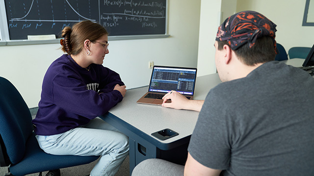 Mathematics students sharing laptop