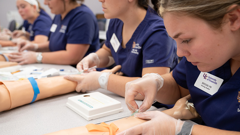 Nursing students practicing injections into fake arms