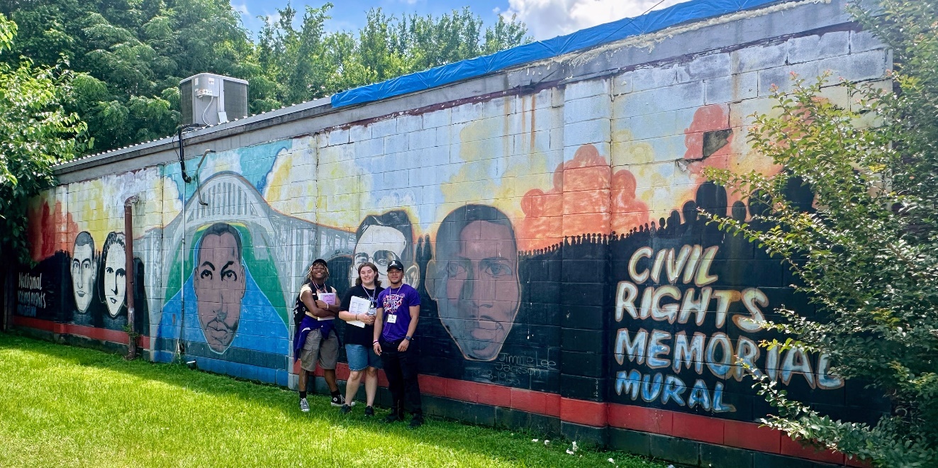 Journey to Justice students standing in front of wall mural