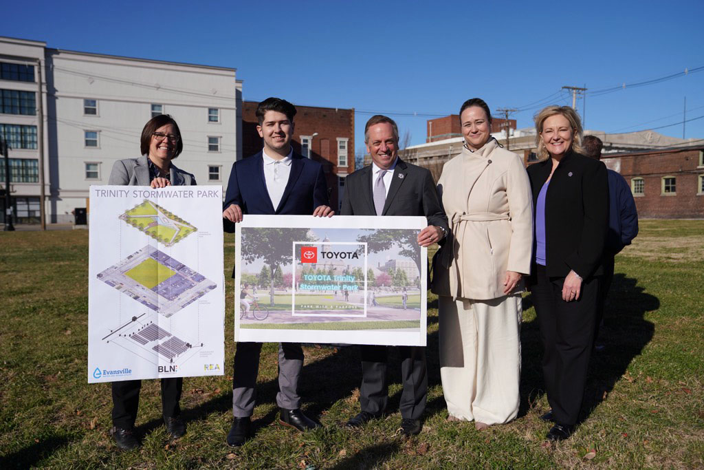 Robert Lopez holding up stormwater signs along with UE President Christopher M. Pietruszkiewicz, Jill Griffin, Erin Lewis, and Brooksie Smith.