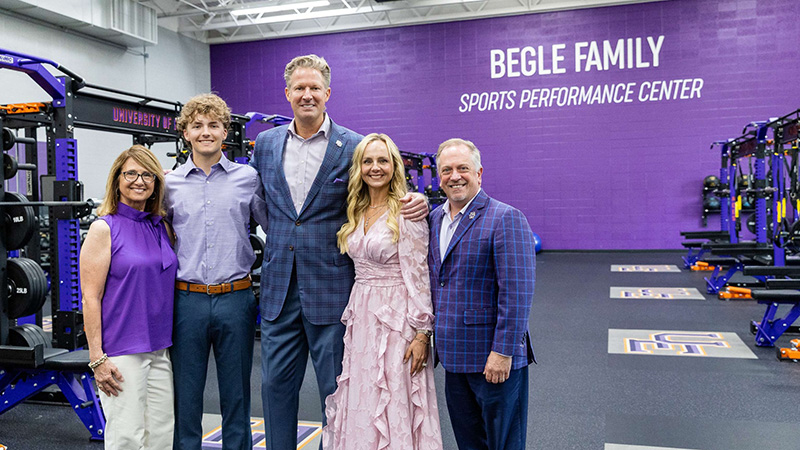 Beagles and UE President and First Lady with the purple wall with the name on it in the background