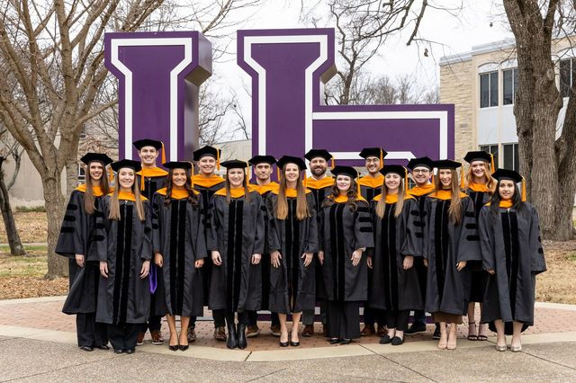 Third cohort group photo in front of UE letters