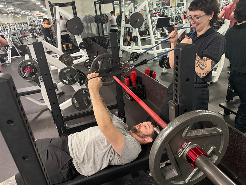 UE PT student assisting a spinal cord injury patient with exercise.