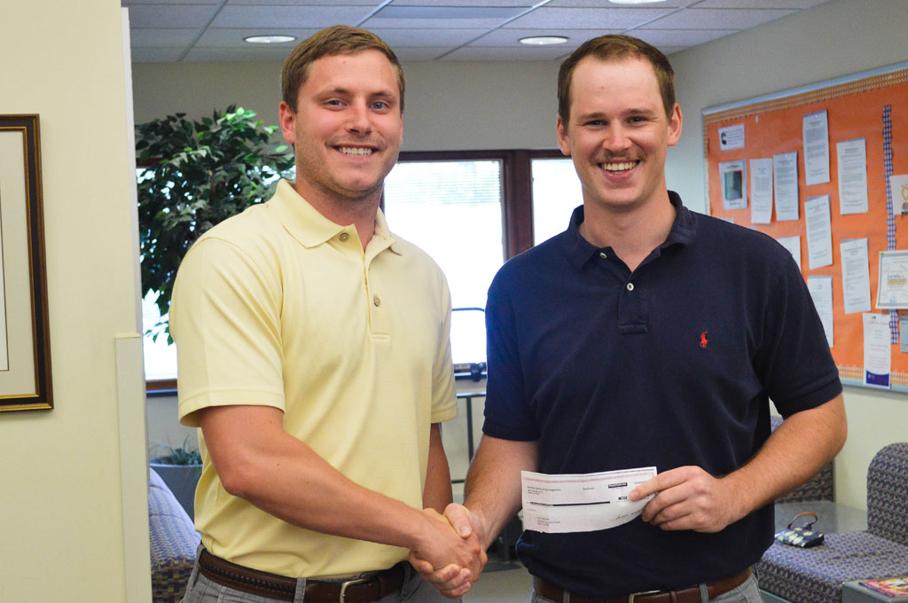 Chris Unzicker shaking hands and holding winning check