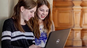 Two female students laughing with laptop
