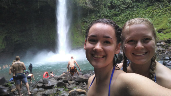 Natalie swimming under a waterfall